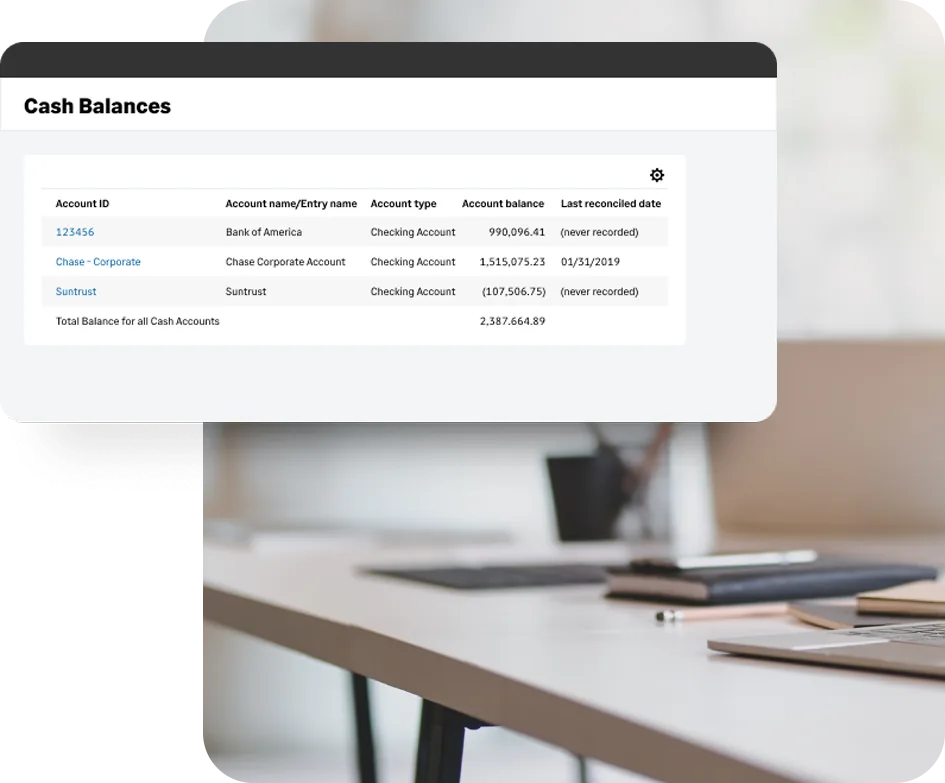 Sage Intacct cash balances screen listing three checking accounts with account balances, a total cash balance and last reconciled dates, displayed above an office desk with a laptop